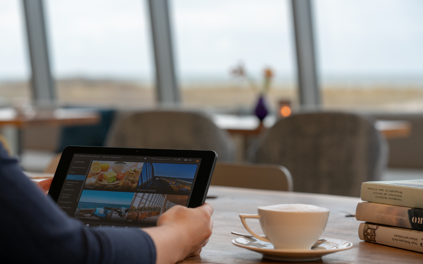  Digitale Gästemappe better.guest auf dem In-Room Tablet wird von Hotelgast im The Grand in den Händen gehalten